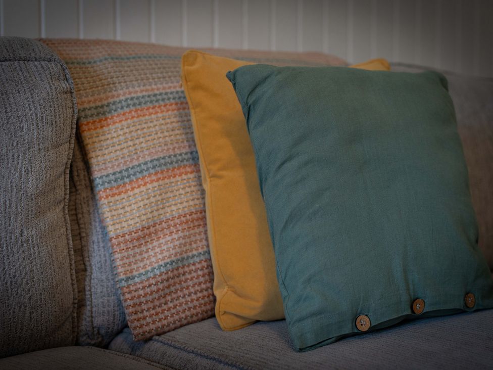 A sofa with cushions and a blanket at The Bothy in Blairgowrie