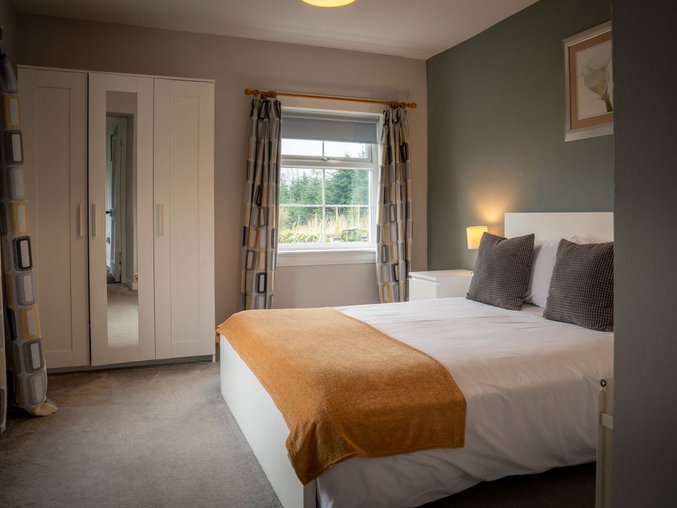 A bedroom with a bed and wardrobe at The Bothy in Blairgowrie