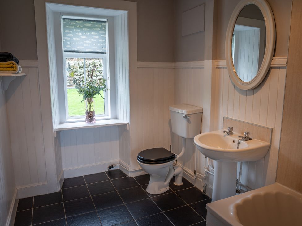 A bathroom with a toilet, sink, and window at The Bothy in Blairgowrie