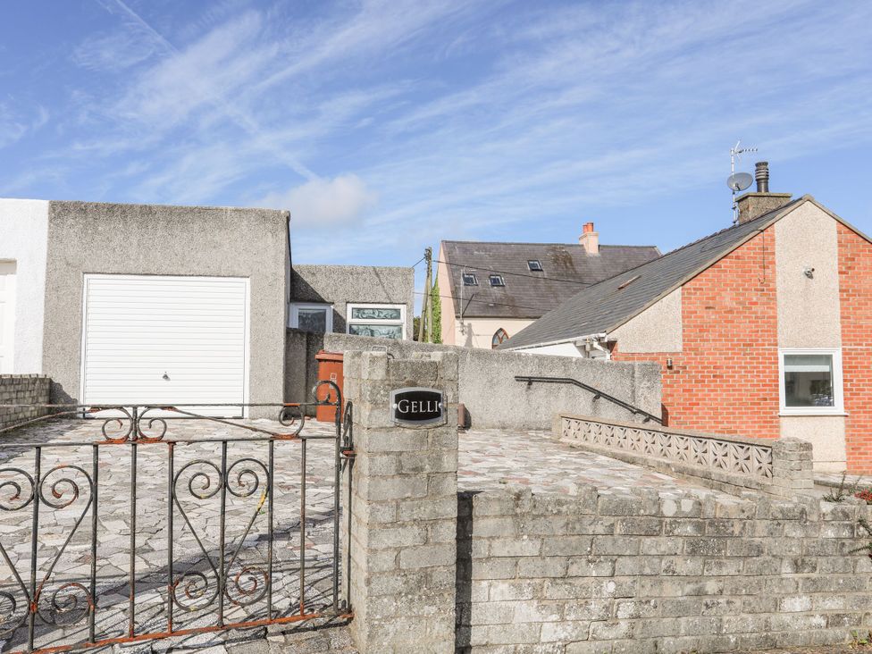 An outdoor view of a house with a garage and a decorative gate at Gelli in Morfa Nefyn