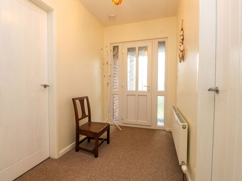 A hallway with a chair and coat rack at Gelli - Morfa Nefyn, Morfa Nefyn