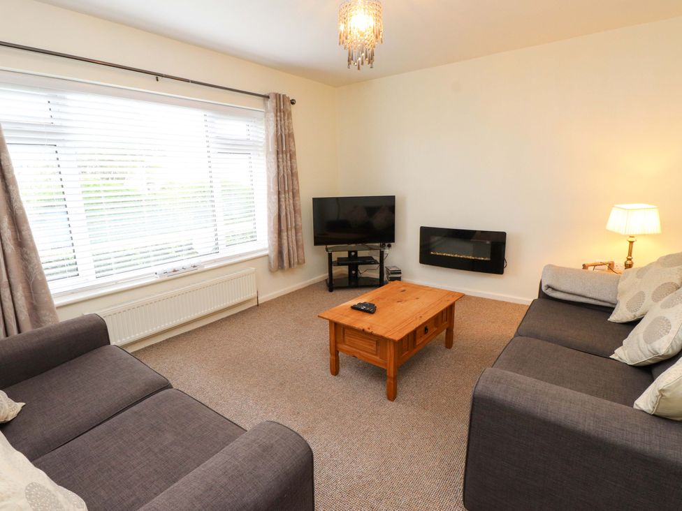 A living room with two sofas, a table and a television at Gelli - Morfa Nefyn in Morfa Nefyn