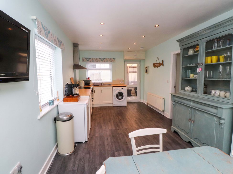 A kitchen with appliances and a dining table at Gelli - Morfa Nefyn in Morfa Nefyn