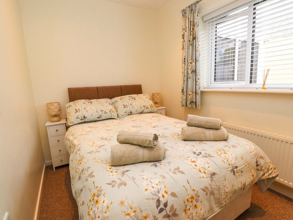 A bedroom with a bed and bedside tables at Gelli - Morfa Nefyn