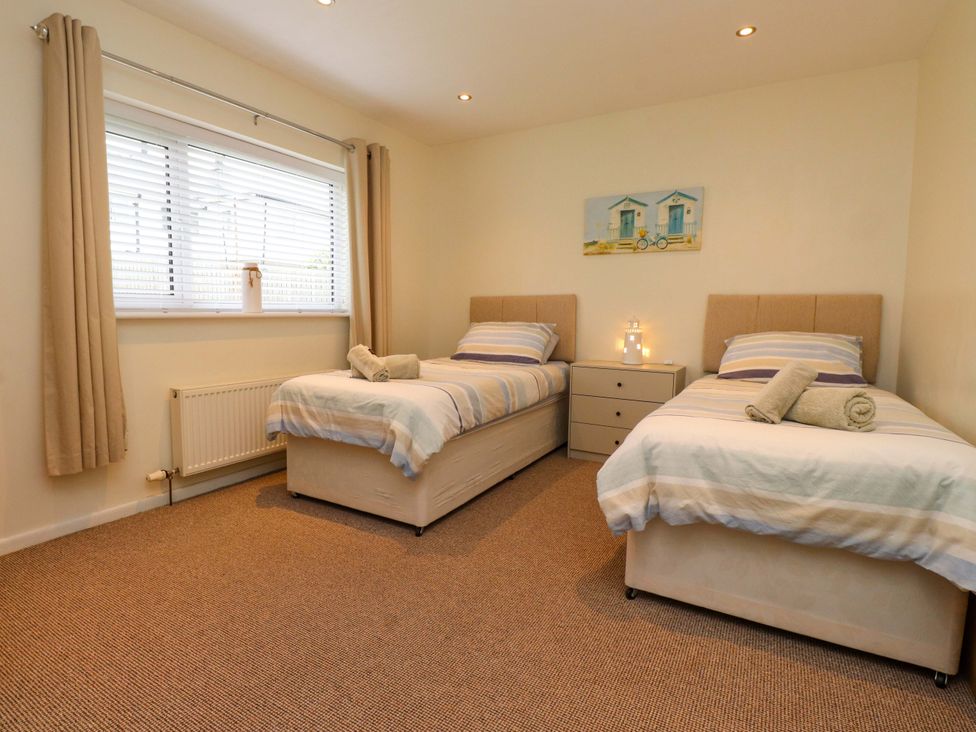 A bedroom with two beds and a bedside table at Gelli - Morfa Nefyn