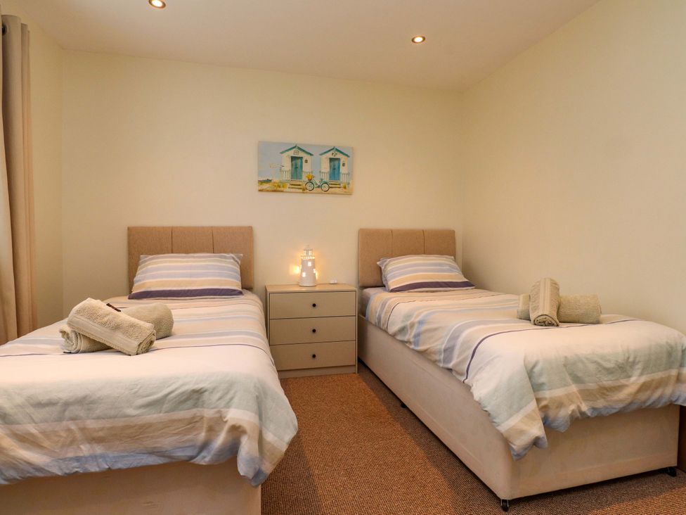 A bedroom with two beds and a nightstand at Gelli - Morfa Nefyn