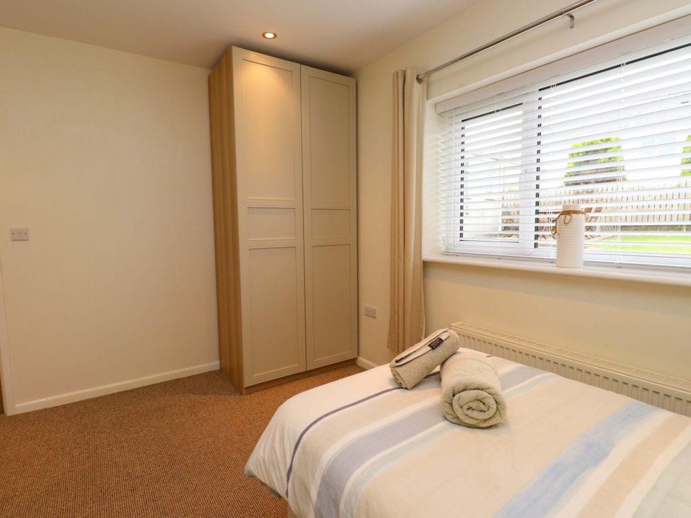 A bedroom with a bed and a wardrobe at Gelli - Morfa Nefyn