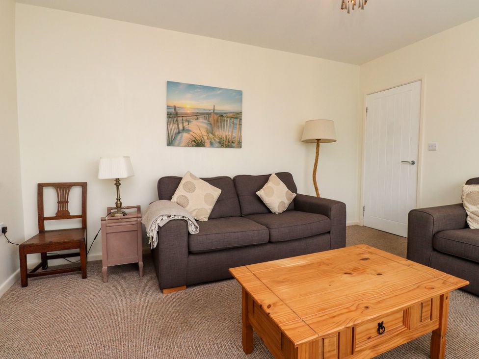 A living room with a sofa, coffee table and lamp at Gelli - Morfa Nefyn