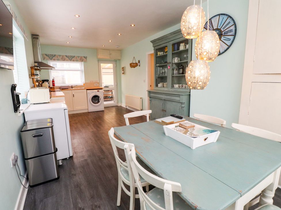 A kitchen with a dining table and appliances at Gelli - Morfa Nefyn