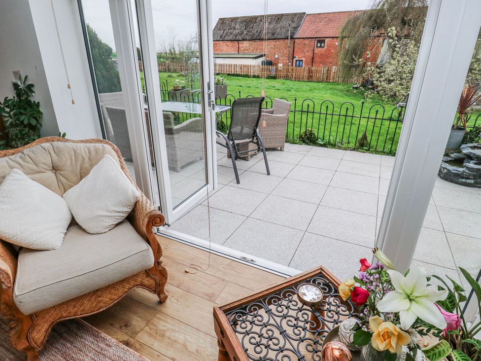 A conservatory with a chair and table overlooking an outdoor area at The Retreat in 