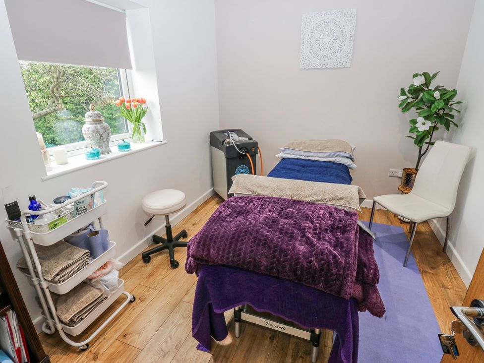 A treatment room with a massage table and a chair at The Retreat in 