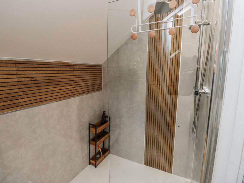 A shower with wooden paneling and a shelf in a bathroom at The Retreat 
