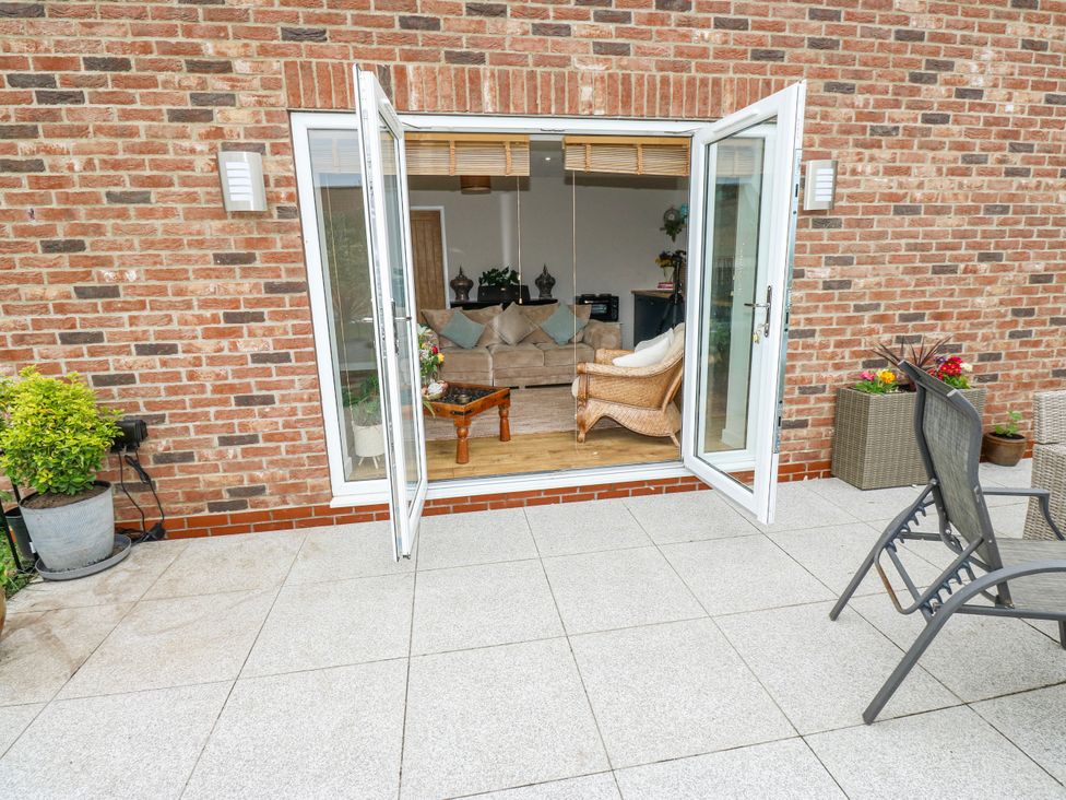 A garden area with doors open to a living room at The Retreat 