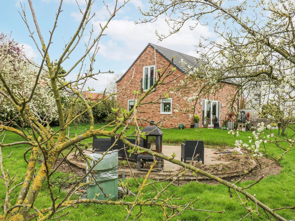 A garden with a house and patio furniture at The Retreat