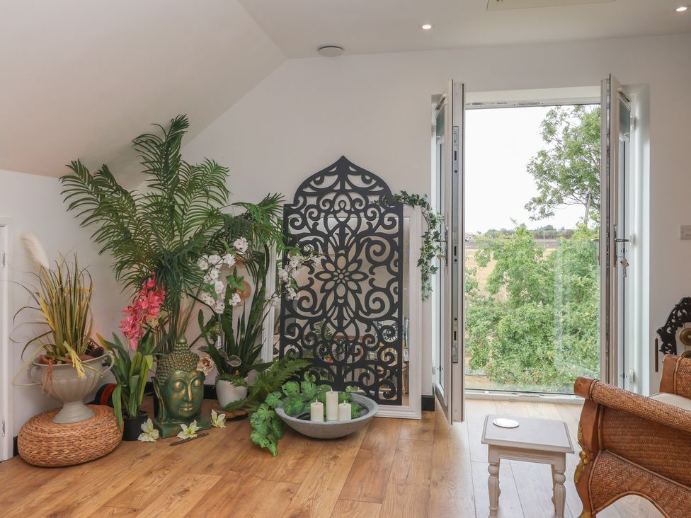 A room with plants, a decorative screen, and a buddha statue at The Retreat in Snaith