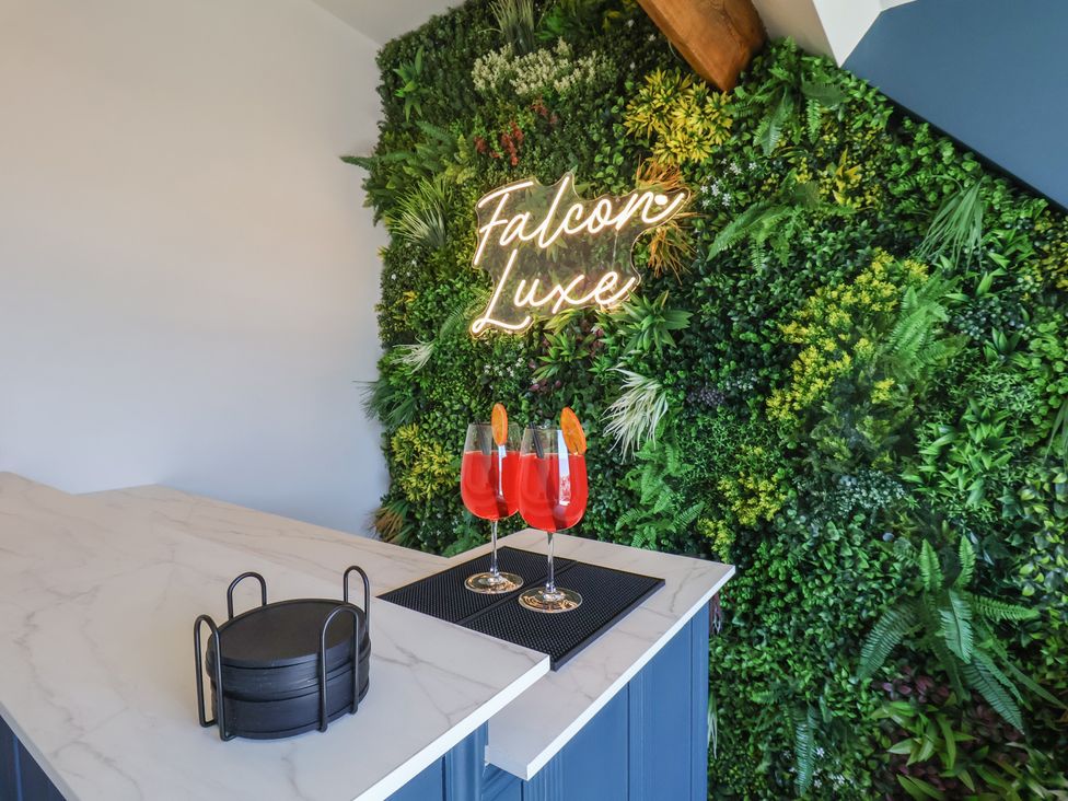A bar with cocktails and a neon sign at Falcon Luxe in Whitby