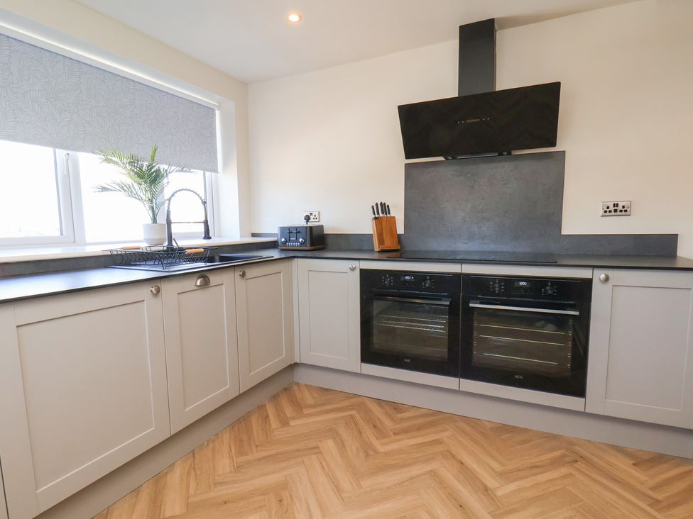 A kitchen with cabinets, sink, and ovens at Falcon Luxe in Whitby