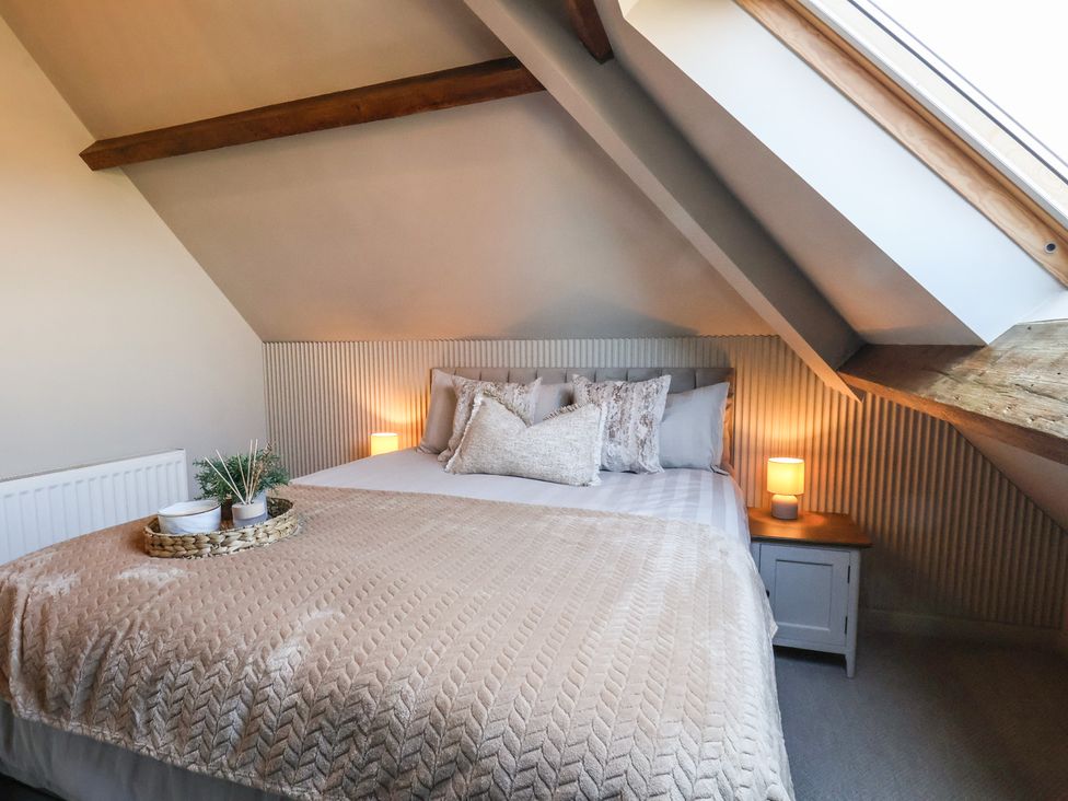 A bedroom with a bed, nightstand, lamp, and plant at Falcon Luxe in Whitby