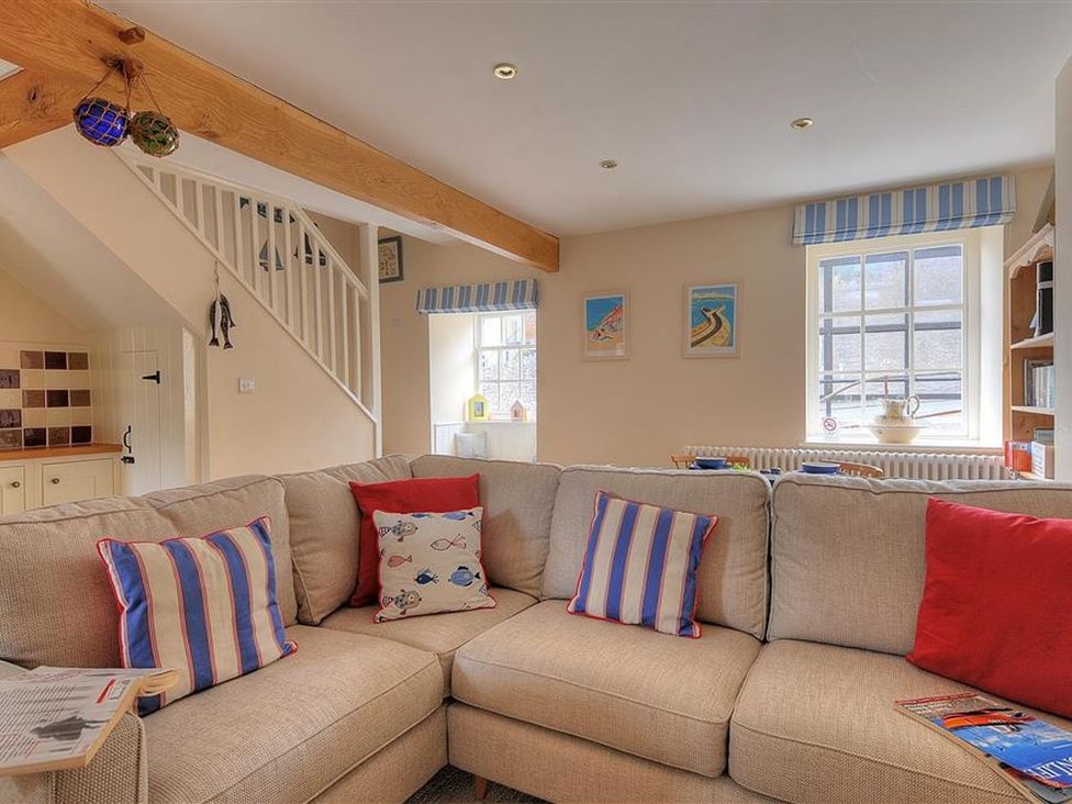 A living room with a sofa and decorative pillows at Half Moon Cottage in Lyme Regis