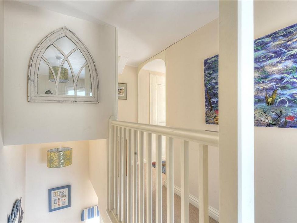 A hallway with a mirror and artwork at Half Moon Cottage in Lyme Regis