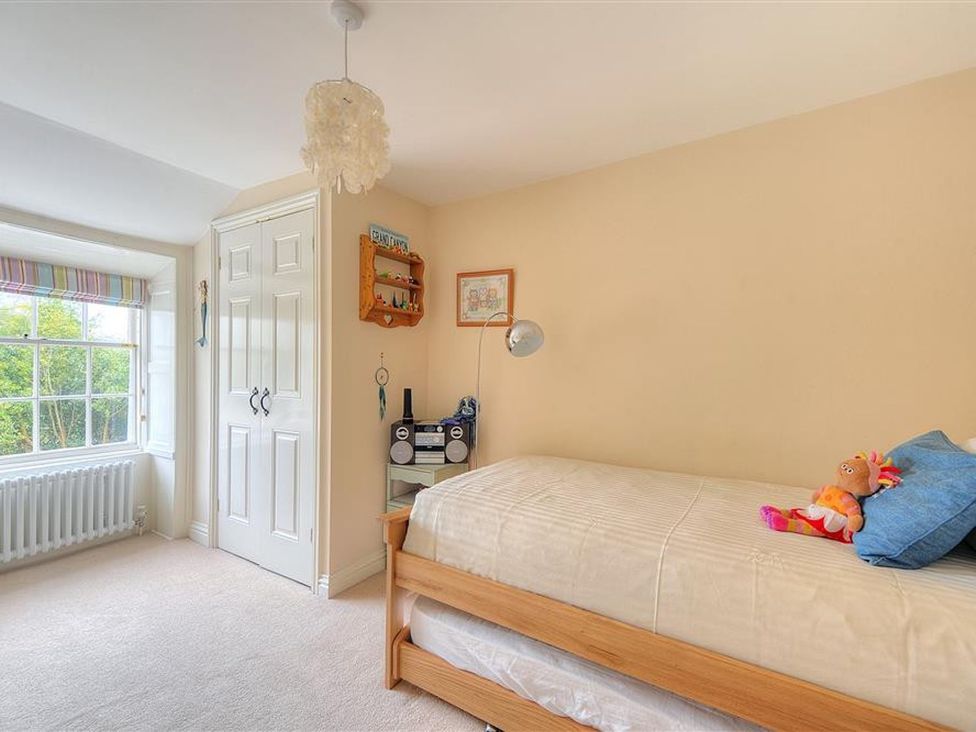 A bedroom with a bed, shelf and stereo at Half Moon Cottage in Lyme Regis