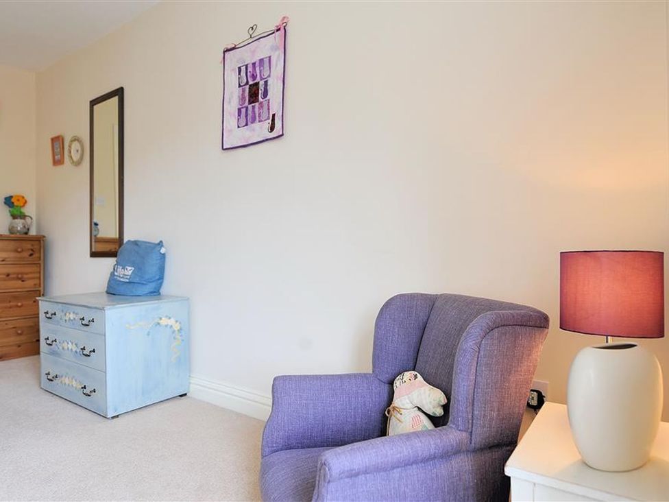 A bedroom with an armchair and decorative items at Half Moon Cottage in Lyme Regis