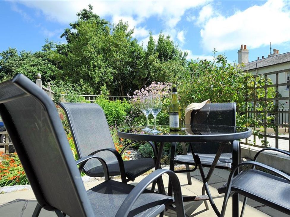 A table with glasses and a bottle in an outdoor seating area at Half Moon Cottage in Lyme Regis