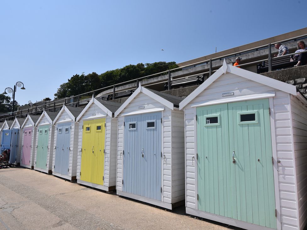 Beach huts lined along a pathway at Half Moon Cottage in Lyme Regis