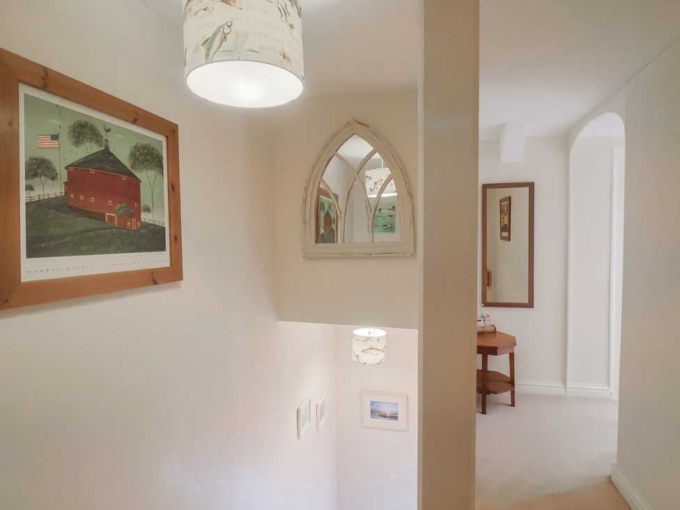 A hallway with a light fixture and framed pictures at Half Moon Cottage in Lyme Regis