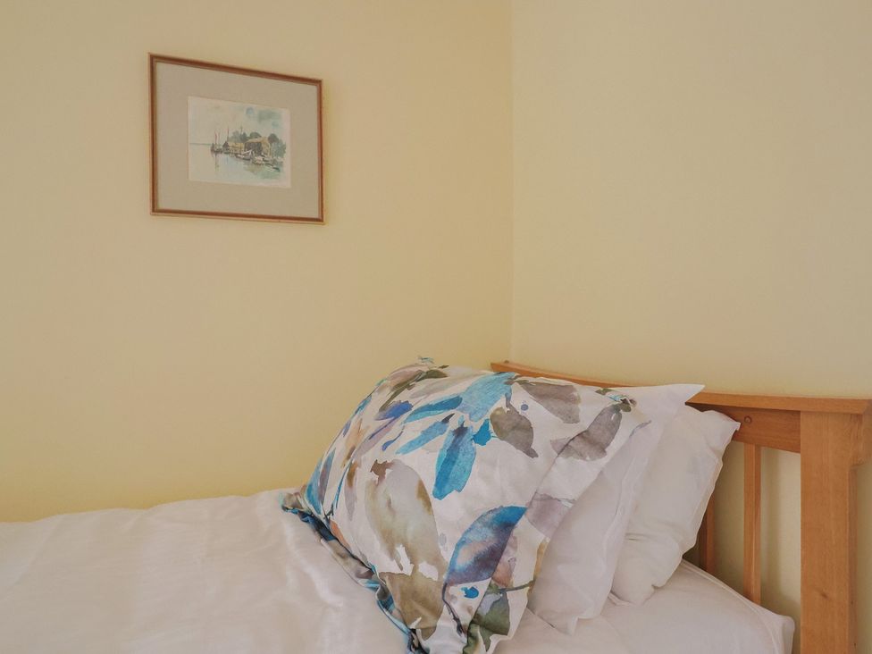 A bed with decorative pillows and wall art at Half Moon Cottage in Lyme Regis