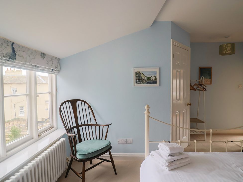 A bedroom with a chair and artwork at Half Moon Cottage Lyme Regis