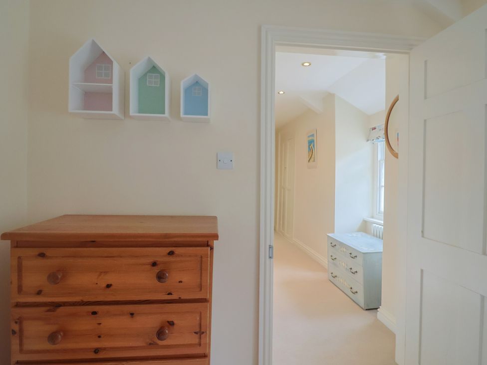 A bedroom with a chest of drawers and decorative shelves at Half Moon Cottage in Lyme Regis