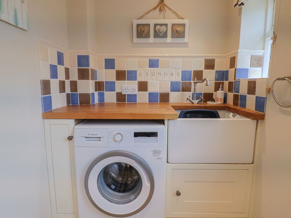 A laundry room with a washing machine and sink at Half Moon Cottage in Lyme Regis