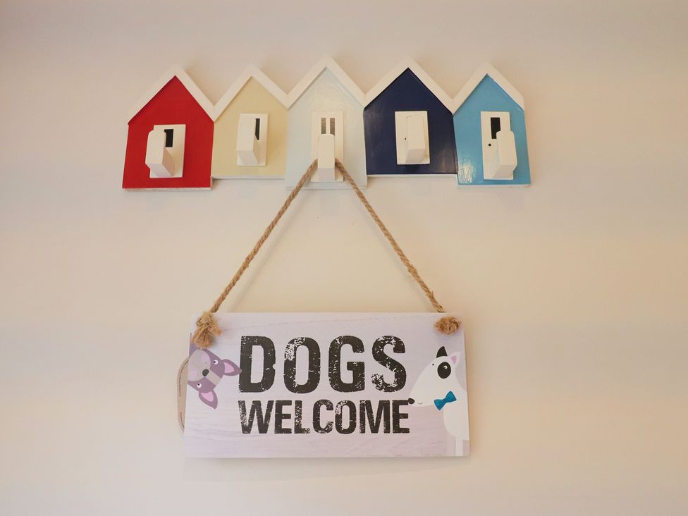 A wall with coat hooks and a dogs welcome sign at Half Moon Cottage in Lyme Regis
