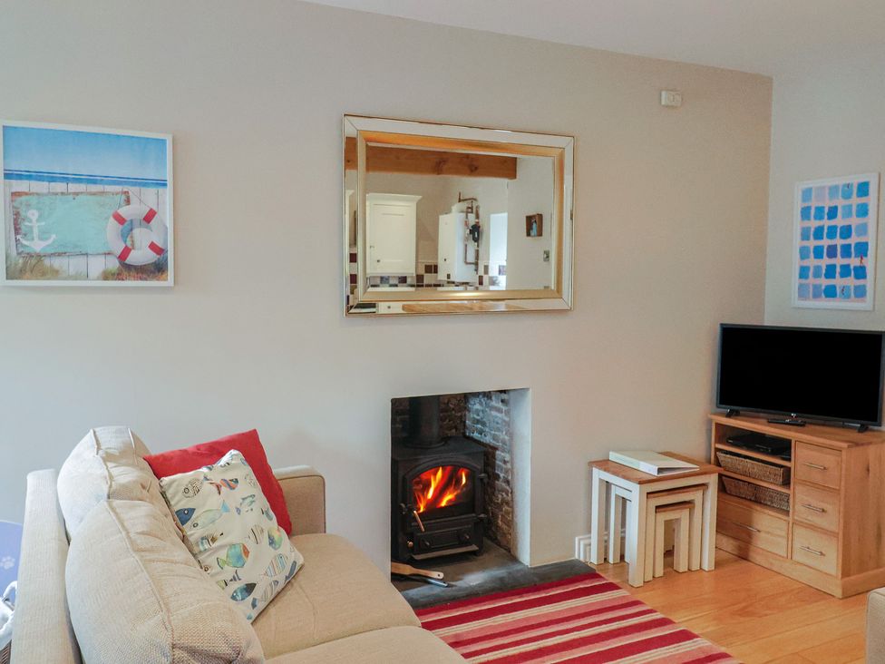A living room with a fireplace and television at Half Moon Cottage in Lyme Regis