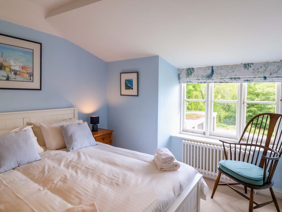A bedroom with a bed and a chair at Half Moon Cottage in Lyme Regis