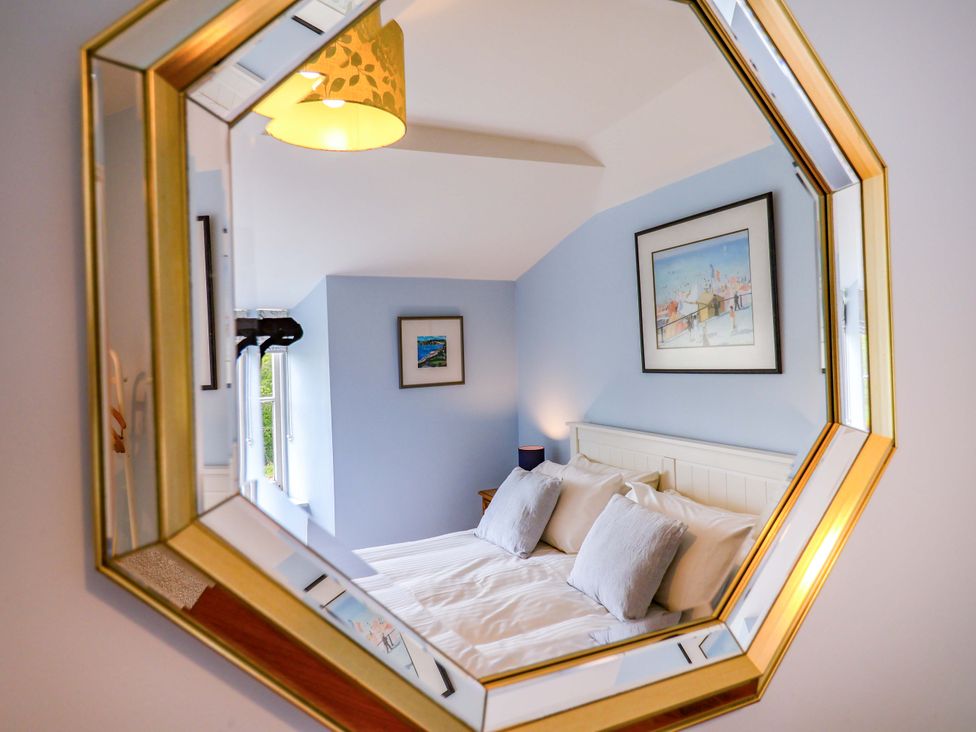 A bedroom with a mirror and painting at Half Moon Cottage Lyme Regis