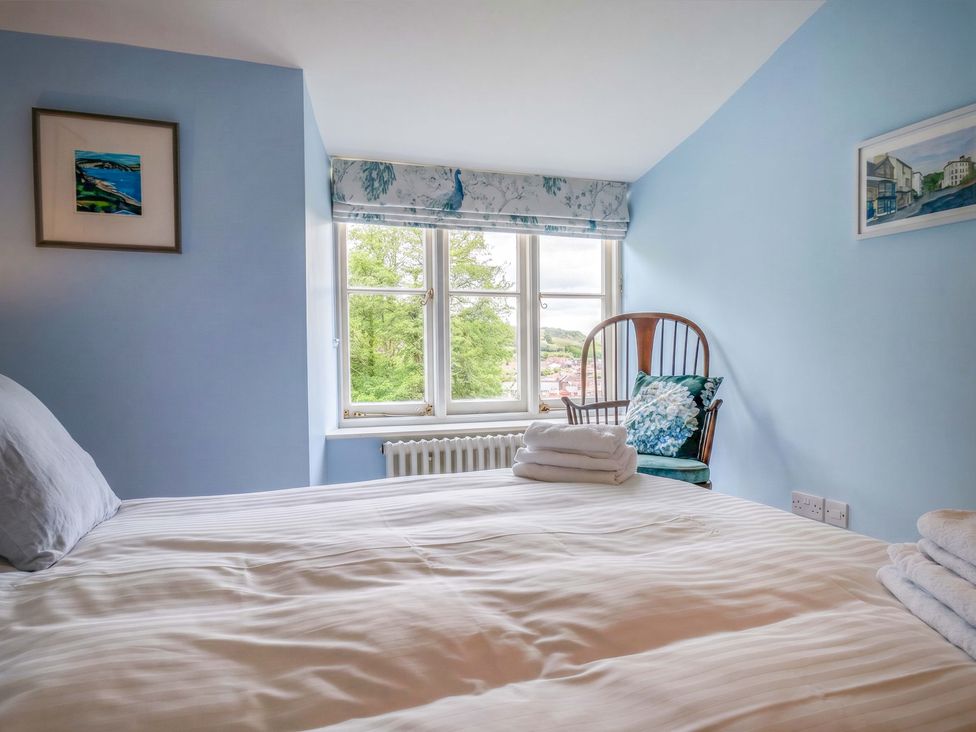 A bedroom with a bed and chair at Half Moon Cottage in Lyme Regis