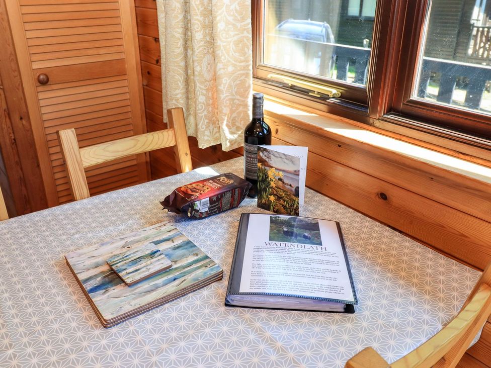 A dining table with a bottle of wine, biscuits, and a menu at Watendlath in Keswick