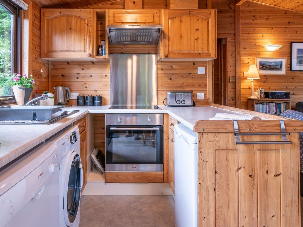 A kitchen with wooden cabinets and appliances at Watendlath in Keswick