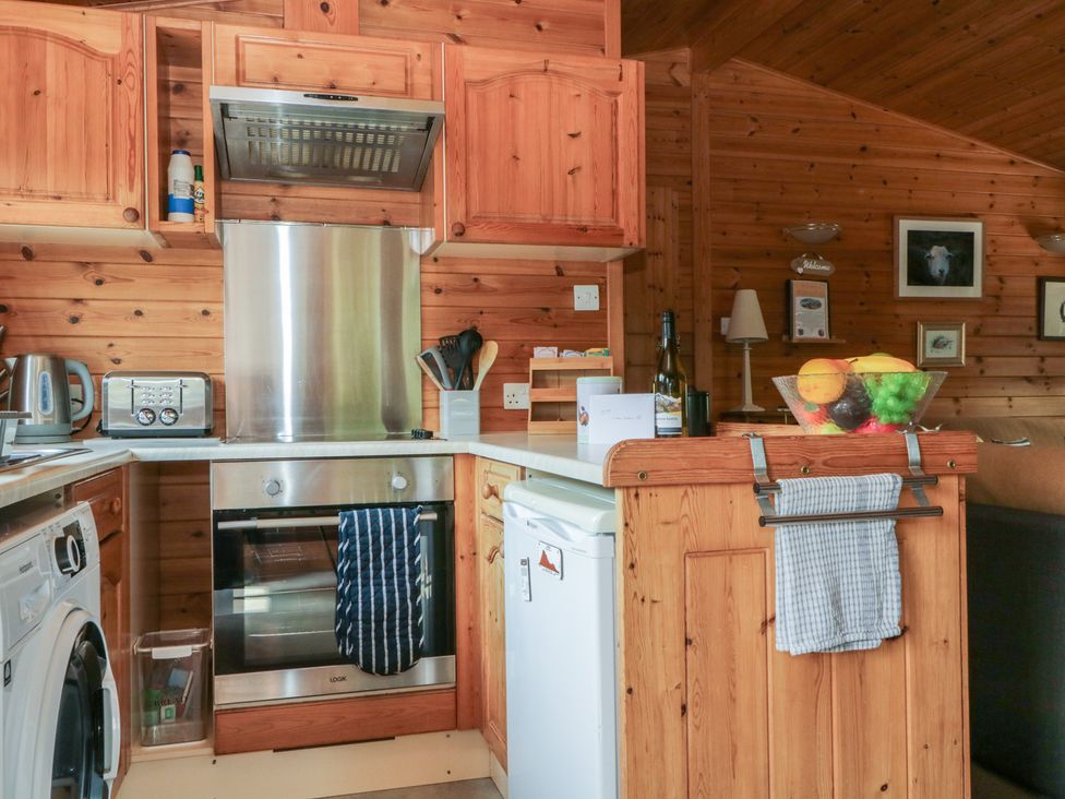 A kitchen with wooden cabinets and appliances at Watendlath in Keswick