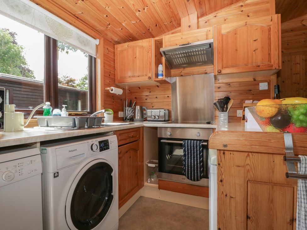 A kitchen with wooden cabinets and appliances at Watendlath in Keswick