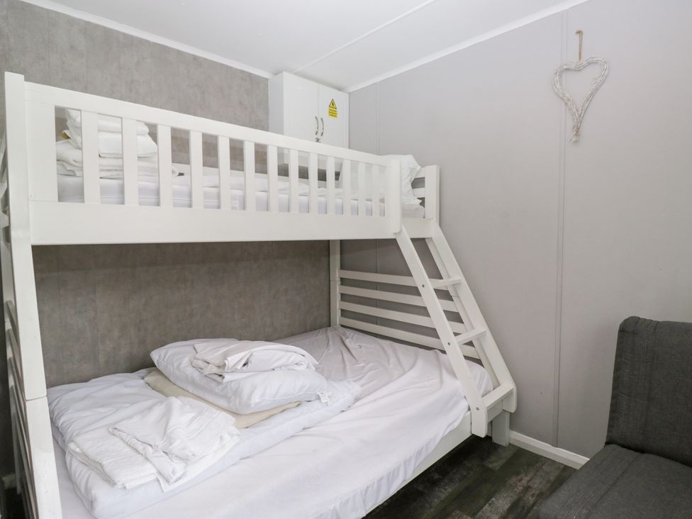 A bunk bed with a sofa in a bedroom at Costapacket in Windermere
