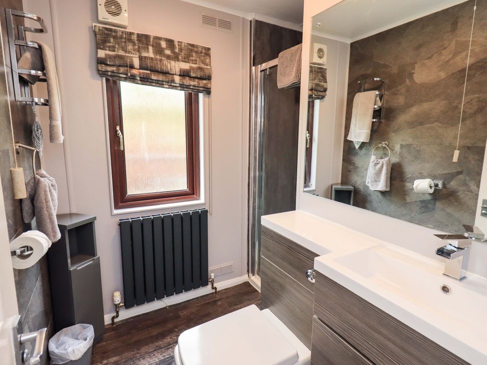 A bathroom with a sink, toilet, and window at Costapacket, Grasmere 12, White Cross Bay near Windermere