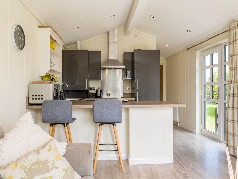 A kitchen with bar stools and modern appliances at Stokesley in Great Ayton