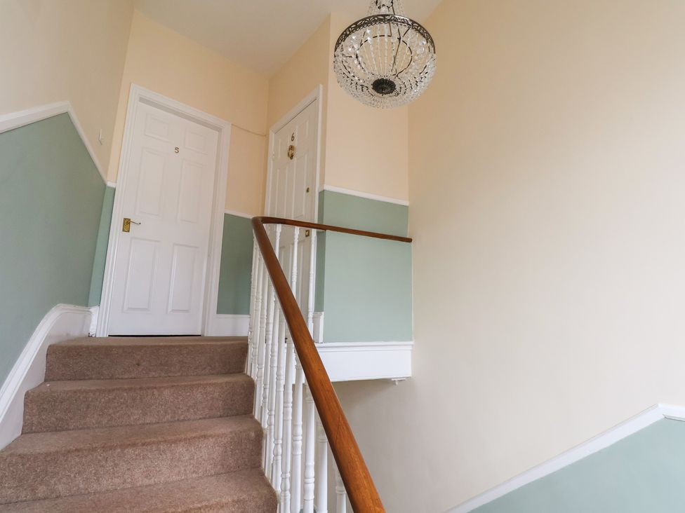 A hallway with a staircase and a chandelier at The Studio on the Crescent in Whitby