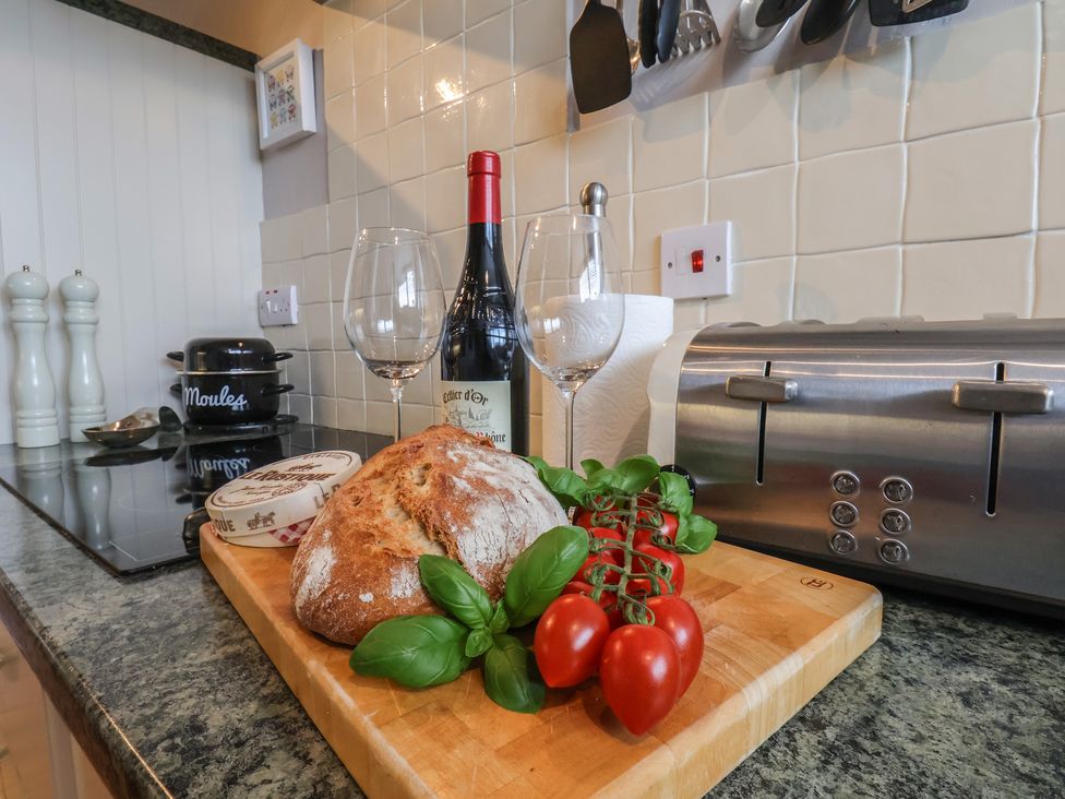 A kitchen counter with bread, tomatoes, wine, and glasses at The Studio on the Crescent in Whitby