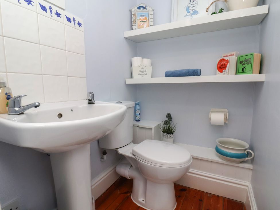 A bathroom with a sink, toilet, and shelves at The Studio on the Crescent in Whitby