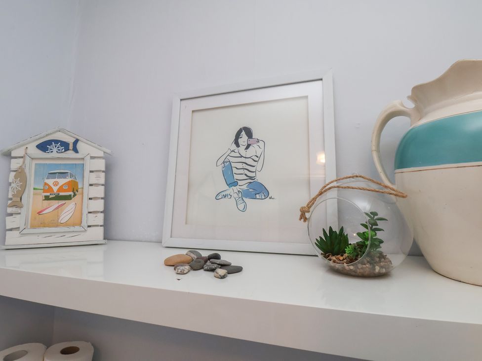 A shelf with a picture frame, decorative house, ceramic jug, and a plant at The Studio on the Crescent in Whitby