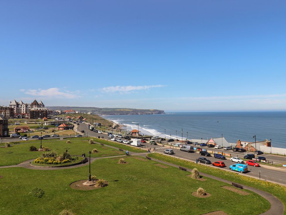 A view of the coastline with cars on the road and grass at The Studio on the Crescent Whitby